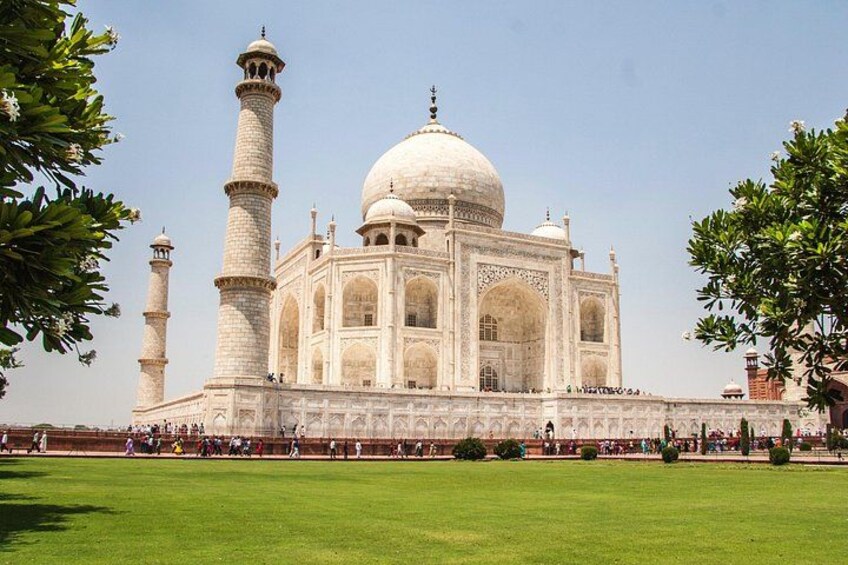 The Taj Mahal with its four minarets and a large central dome, surrounded by a green lawn. 3