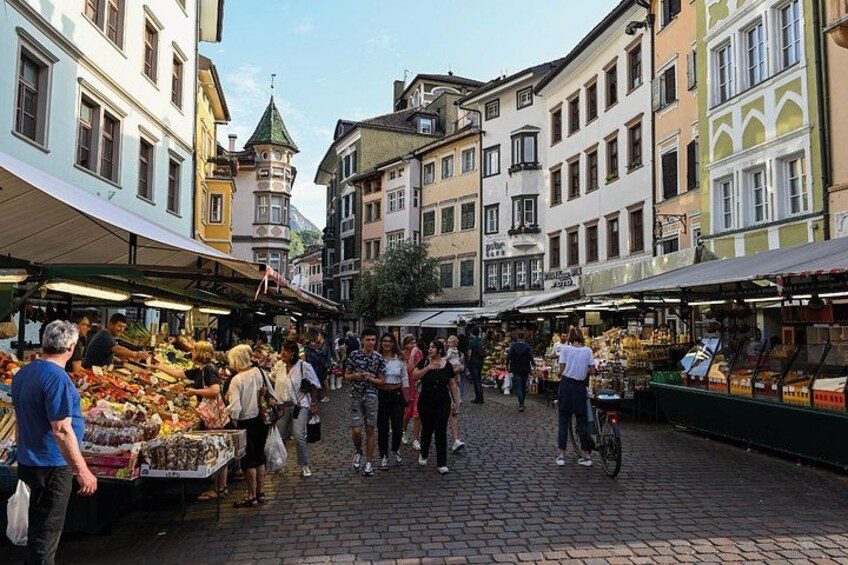 A bustling market street with people shopping and vendors selling goods. 2