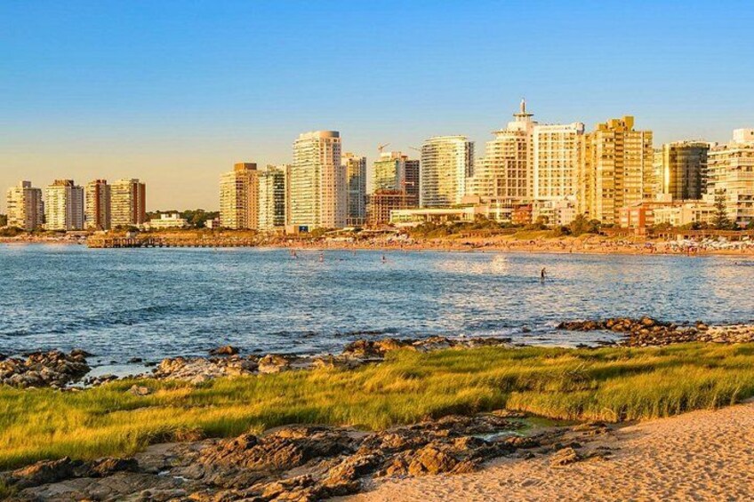 Un paisaje costero con rascacielos, una playa de arena y un litoral rocoso. 4