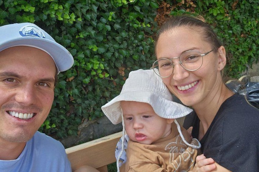 Una persona con un cappello bianco e un bambino vestito di marrone seduti su una panchina. 2