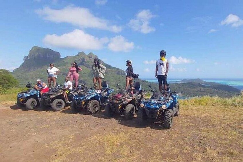 A group of people on ATVs on a dirt path with a mountainous landscape in the background. 4