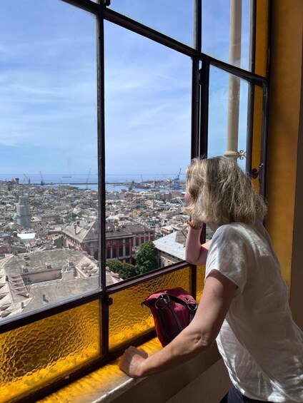 A person looking out of a window at a cityscape with buildings and cranes. 4