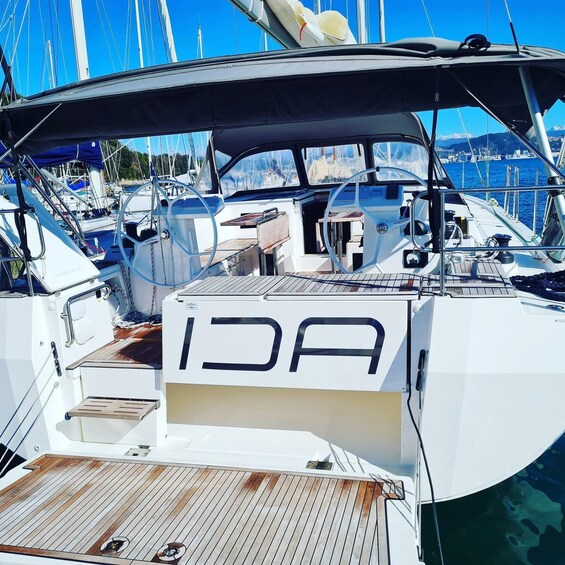A white yacht docked at a marina with other boats, a wooden deck, and a clear blue sky. 1