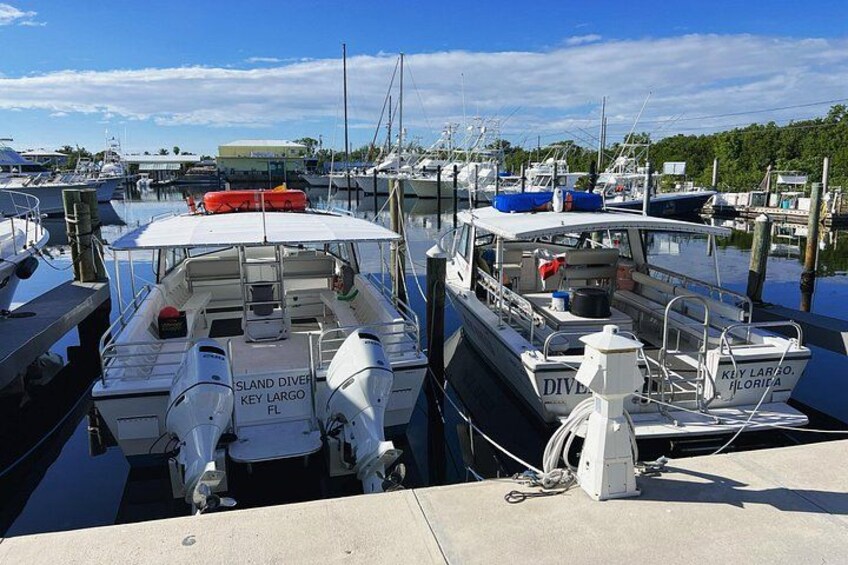 Ein Yachthafen mit mehreren angemeldeten Booten, darunter ein weißes Boot mit der Aufschrift 'ISLAND DIVER KEY LARGO FL'. 4