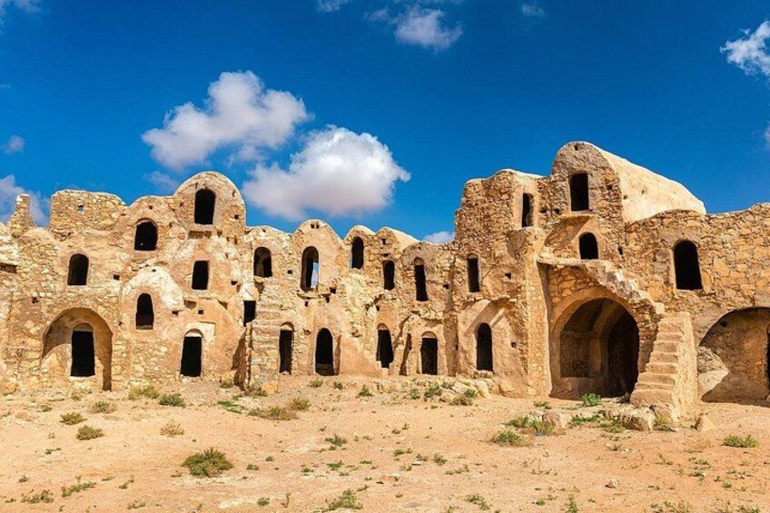 Ancient stone ruins with multiple arches and windows against a clear blue sky. 4