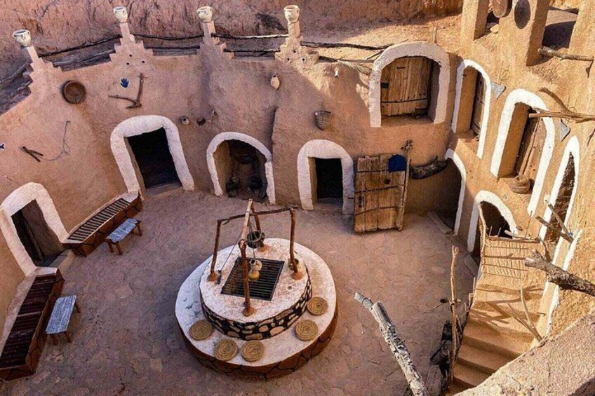 A traditional mud-brick courtyard with arched doorways, a central well, and a staircase. 3