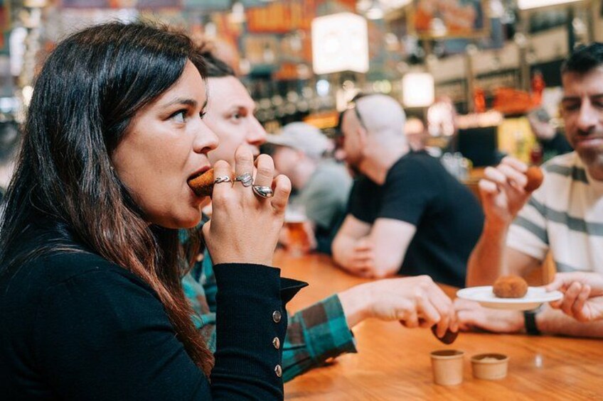 A person eating at a table in a busy indoor setting. 5