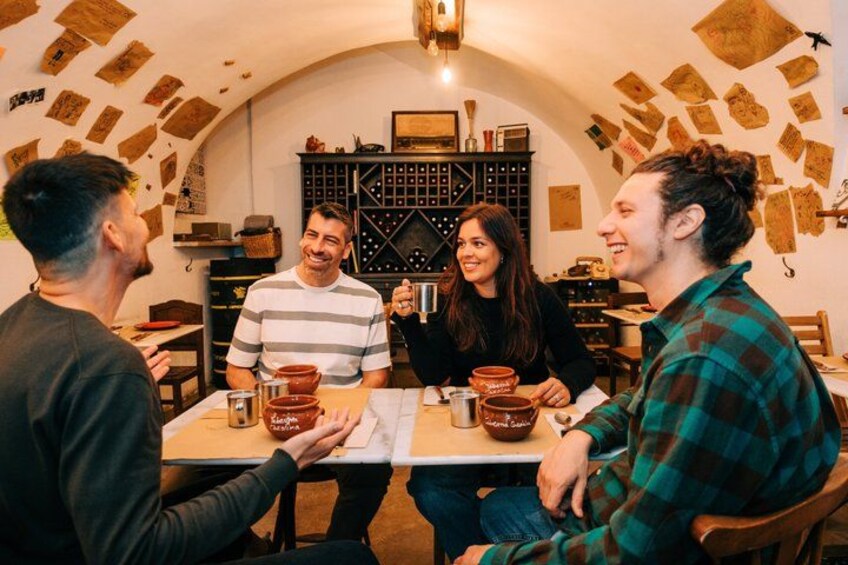 A group of people sitting around a table with pottery and wine glasses. 4