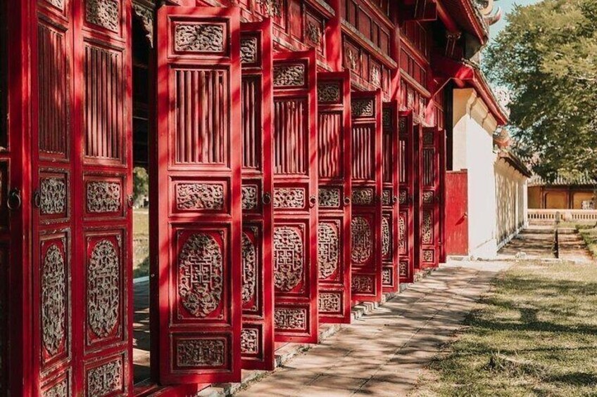 Una hilera de puertas de madera roja con intrincados grabados, que dan acceso a un edificio tradicional. 5