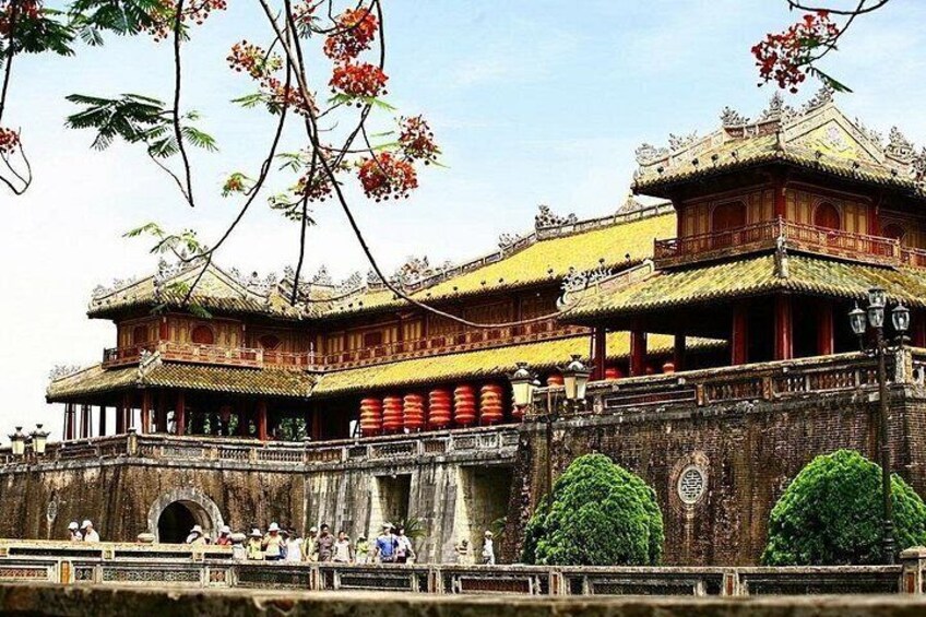 Un edificio tradicional de varios niveles con arquitectura ornamentada, un muro de piedra y un canal al frente. 2