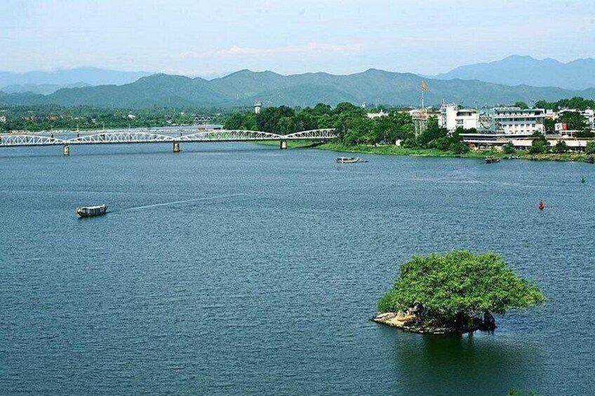 Un río con una pequeña isla, un puente y montañas a la distancia. 4