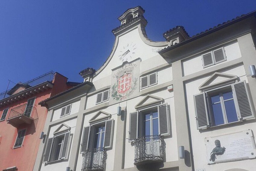 A building with a crest, shutters, and a balcony. 2