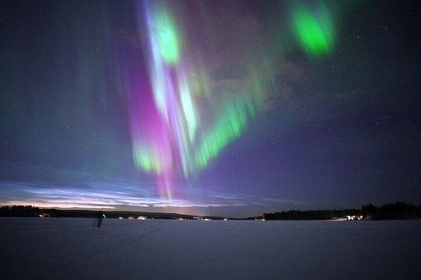 The Northern Lights over a frozen landscape with a distant shoreline. 1