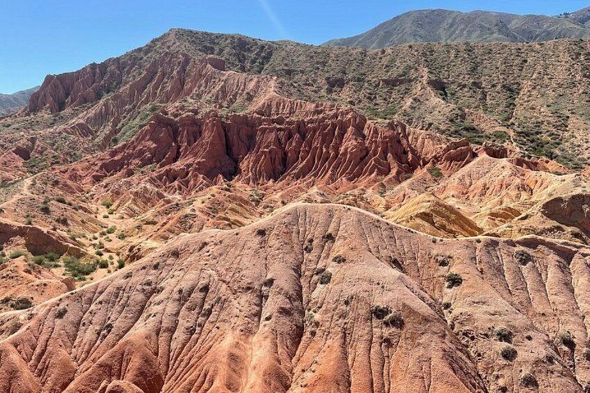 A rugged desert landscape with layered rock formations and sparse vegetation. 5