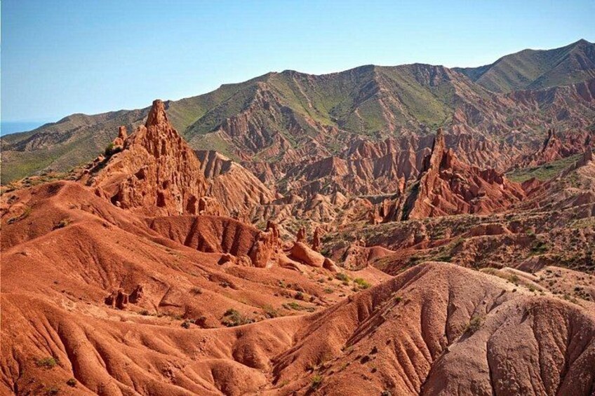 A rugged landscape with red rock formations and distant mountains. 2