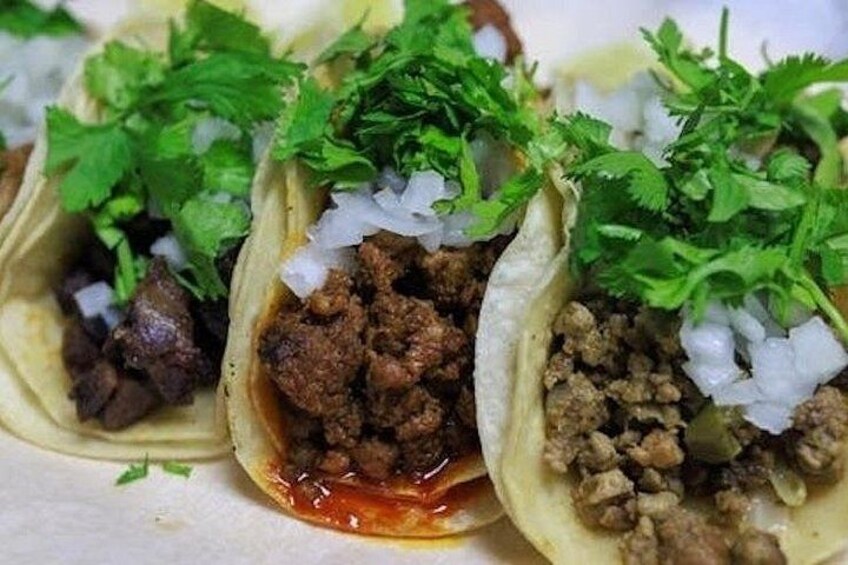 Three tacos with meat, onions, and cilantro. 5