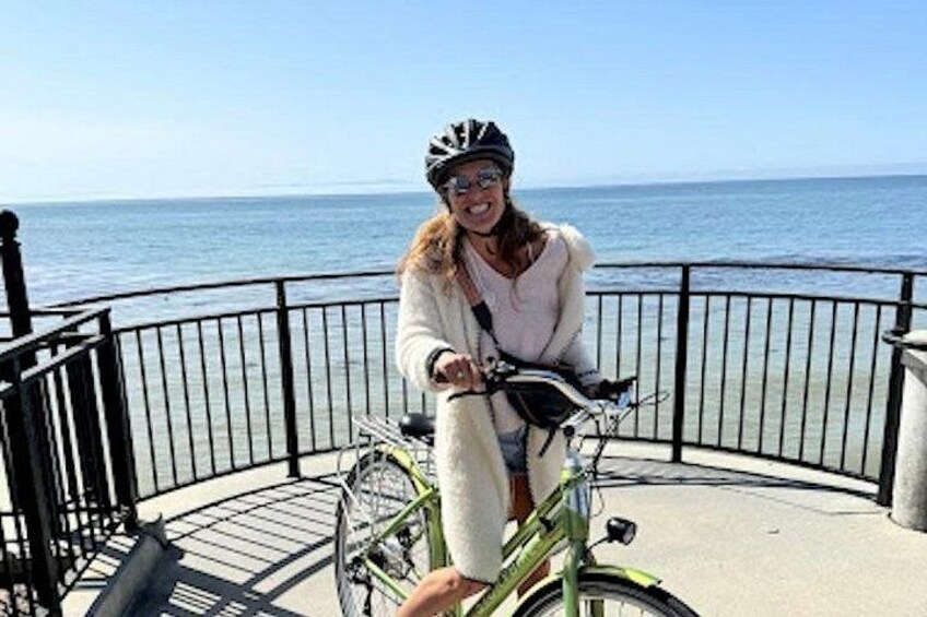 A person riding a bicycle on a paved path near a body of water. 4