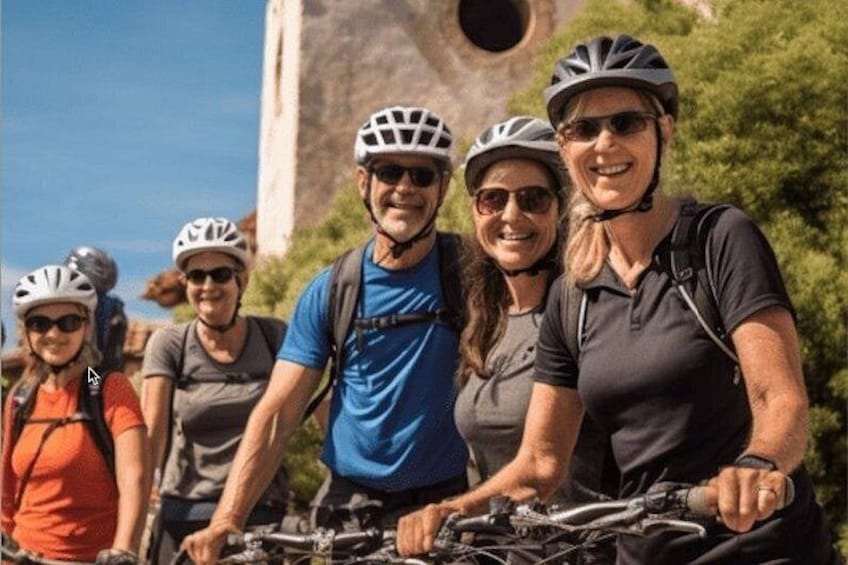 A group of people on bicycles with a large rock formation in the background. 2
