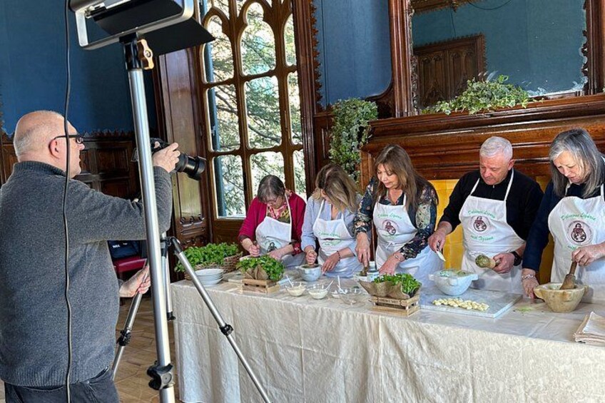 A group of people wearing aprons, engaged in food preparation at a table with vegetables and kitchen tools. 4