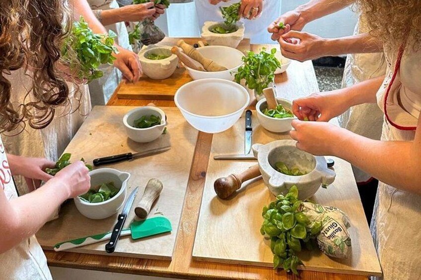 A group of people preparing food with fresh herbs and vegetables on a wooden table. 1
