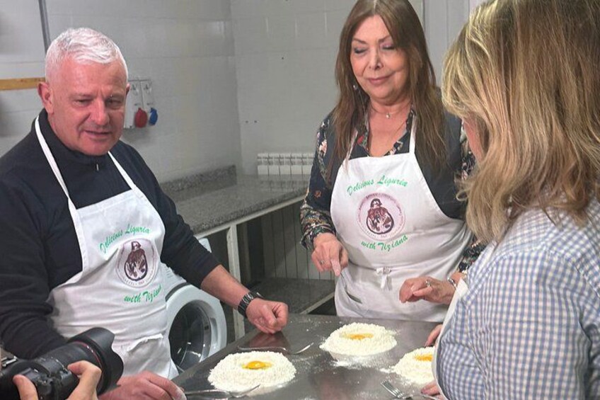 People wearing aprons with logos, working on a kitchen counter with dough and eggs. 3