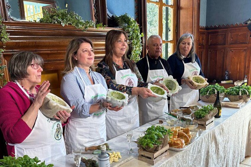 A group of people holding bowls of green pesto at a table with various ingredients and tools. 2