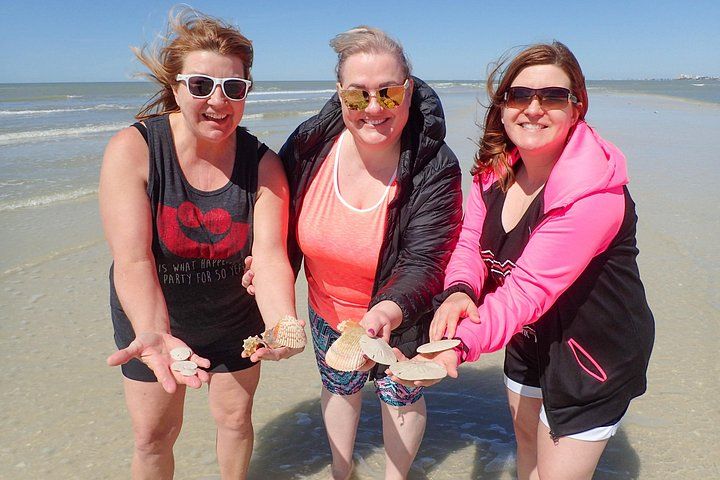 Drie mensen op het strand met schelpen. 4