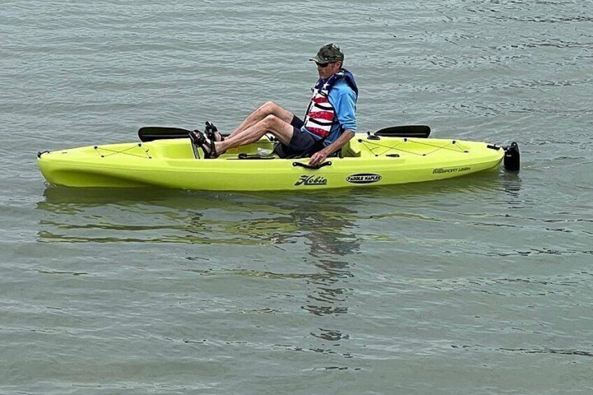 A person sitting on a yellow kayak on calm water. 4