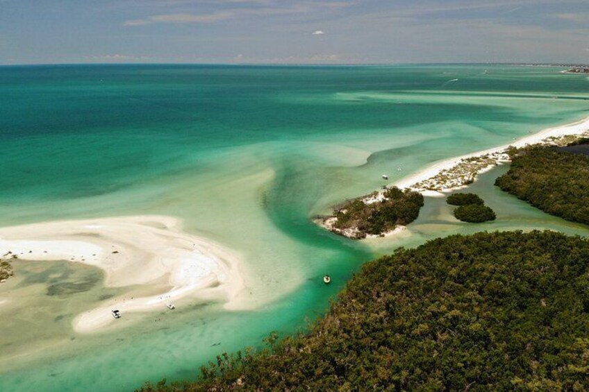 Een kustlandschap met helder turquoise water, zandstranden en weelderige groene begroeiing. 3