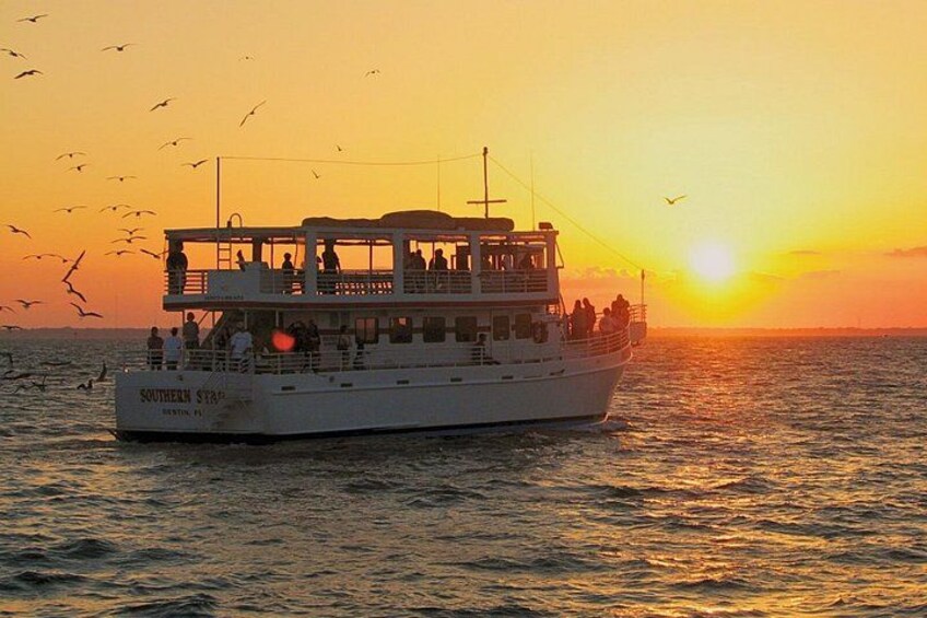 Un barco con pasajeros navegando sobre el agua al atardecer. 1