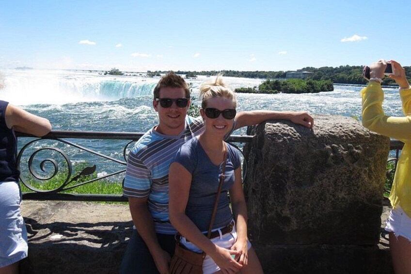 A couple sitting by a railing overlooking a waterfall. 2