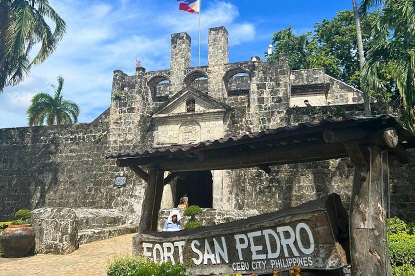 Eine historische SteinFestung mit einer Flagge, beschriftet mit 'FORT SAN PEDRO CEBU CITY PHILIPPINES'. 3