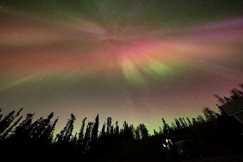 A night sky with the aurora borealis, a forested landscape, and a vehicle. 4