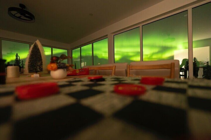 A living room with a checkered floor, a Christmas tree, and a view of the Northern Lights. 2