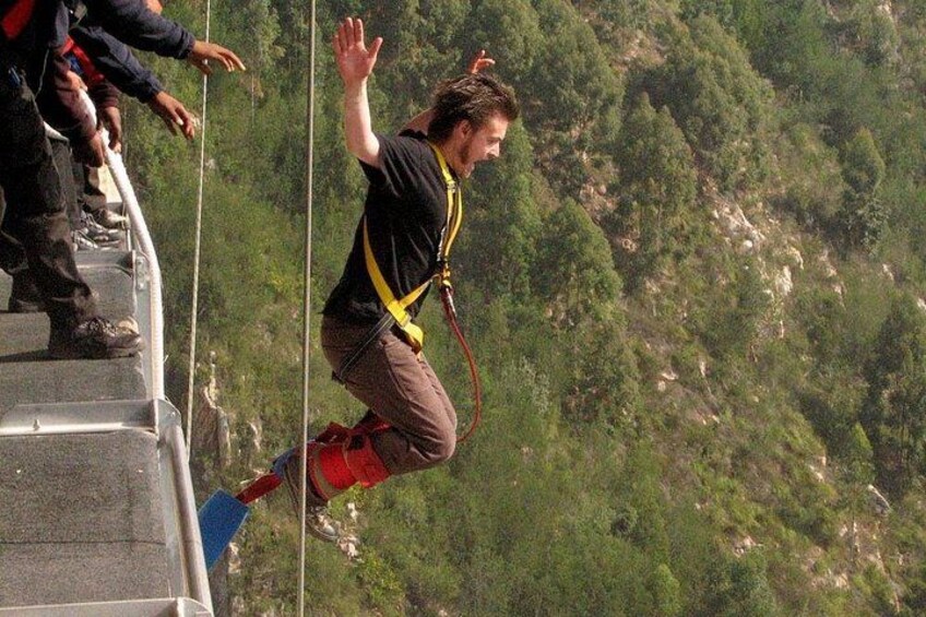 A person bungee jumping with a harness and safety gear, with a mountainous landscape in the background. 4