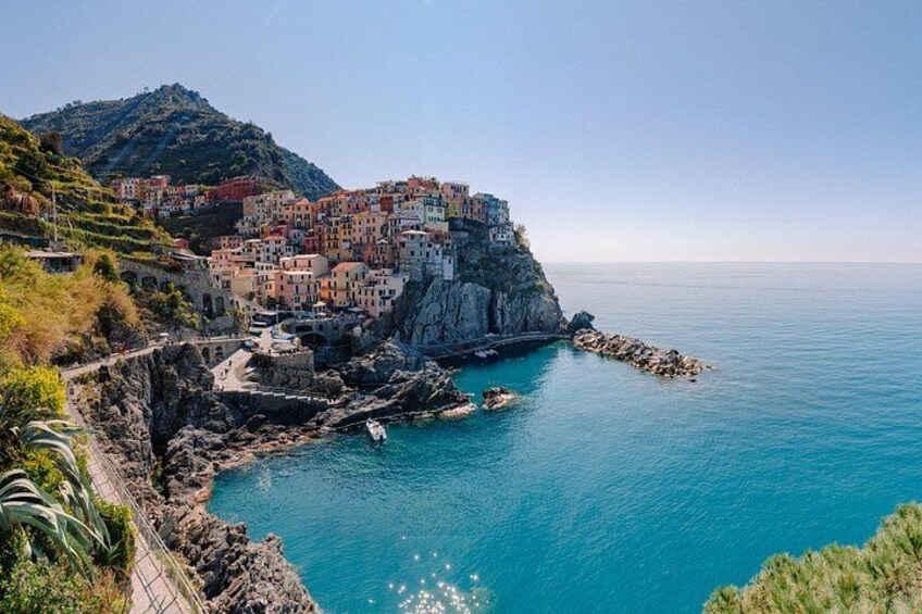 A coastal town with colorful buildings perched on a cliff, a clear blue sea, and rocky shores. 3