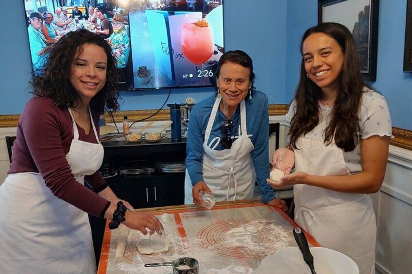 Three people in aprons working with dough on a table. 1