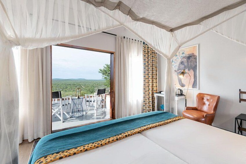 A bedroom with a large bed, a chair, a table, and a view of the outdoors. 5