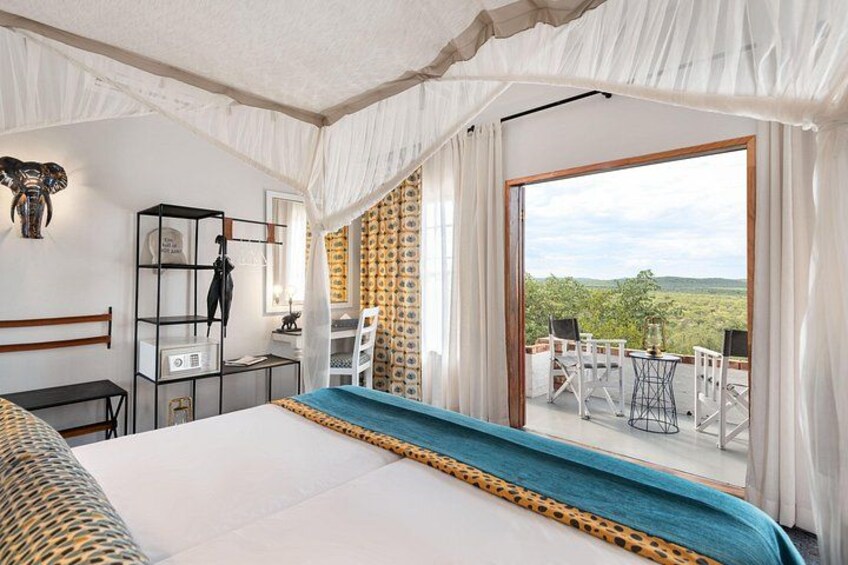 A bedroom with a large bed, a wardrobe, a desk, and a balcony with a view of the countryside. 4