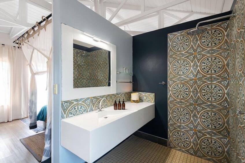 A bathroom with a white sink, a mirror, patterned tiles, and a shower curtain. 3