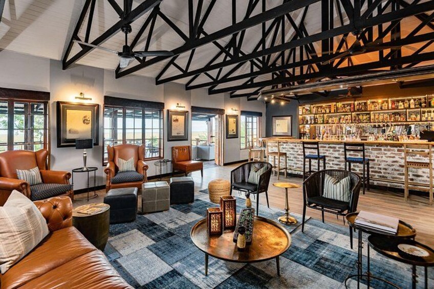 A modern interior with leather sofas, round coffee tables, and a bar area with shelves of books and bottles. 2