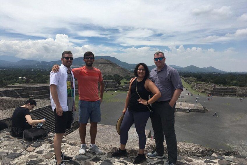 Un gruppo di persone in piedi su un sito storico, con rovine sullo sfondo. 3