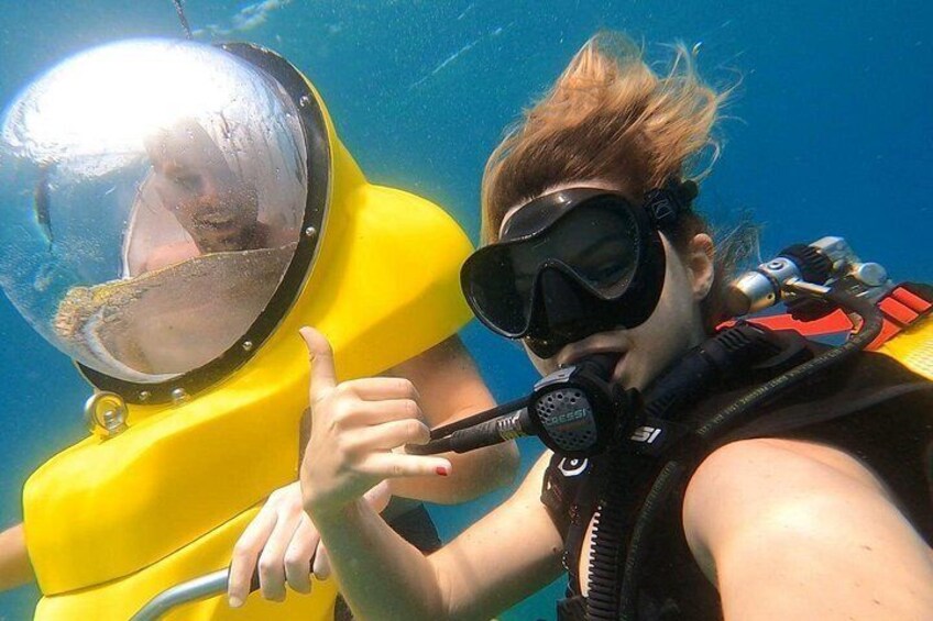 A person in a yellow diving suit and a scuba mask, holding a microphone. 4