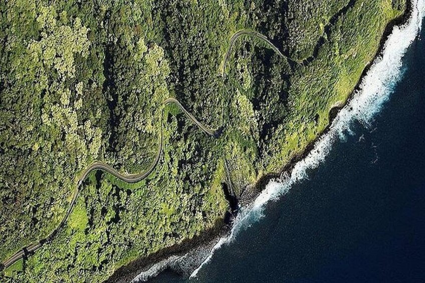 A winding road along a coastal forested area with a view of the ocean. 2