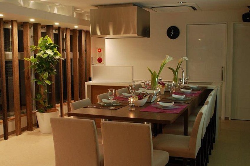 Un comedor moderno con una larga mesa dispuesta para una comida, rodeada de sillas. 2