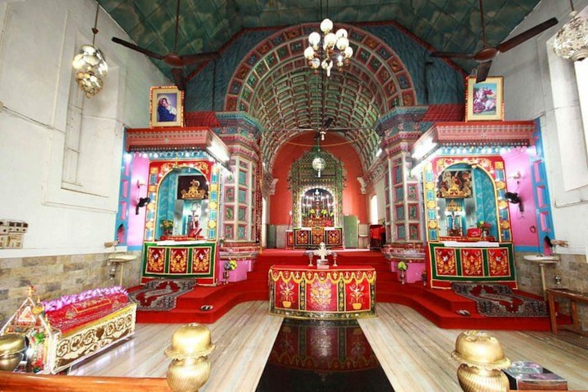 A temple interior with ornate decorations, a central altar, and a red carpet. 3