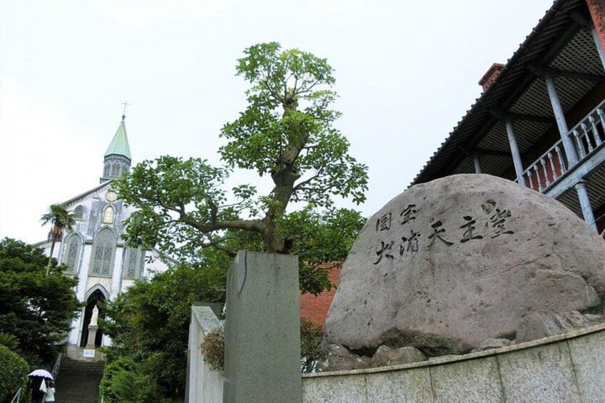 A large stone with Chinese characters, a tree, and a church with a green spire. 2