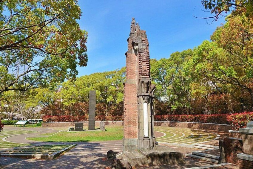 A brick tower with a pointed roof, surrounded by trees and a landscaped area with pathways. 5