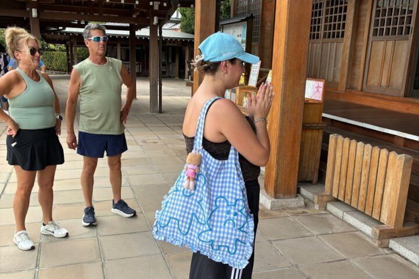 Une personne portant une casquette bleue et un sac à carreaux, debout devant une structure en bois sur laquelle est apposée une enseigne. 4