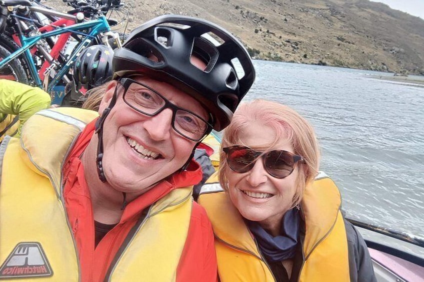 Two people wearing life jackets and helmets on a boat. 5